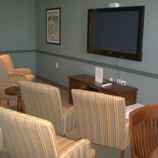 A cozy waiting room with several chairs facing a large wall-mounted television.