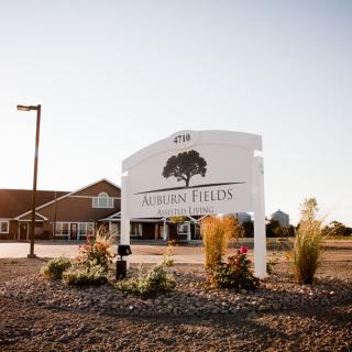 A building with a prominent sign in front, surrounded by landscaping under a clear sky.