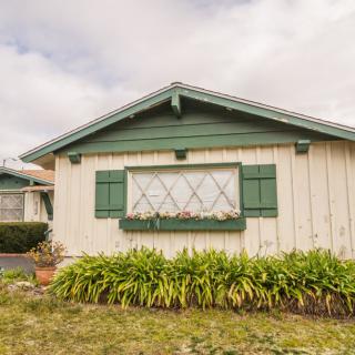 A quaint house with green shutters and a small garden.