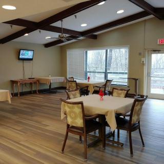 A cozy dining area with tables, chairs, and a television.