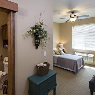 A cozy bedroom with a bed, ceiling fan, and decorative elements.