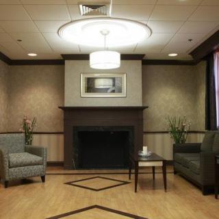 A cozy living room featuring a modern fireplace, two sofas, and a central coffee table under a contemporary ceiling light.