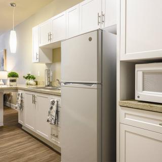 A modern kitchen featuring white cabinetry and stainless steel appliances, including a refrigerator and microwave.