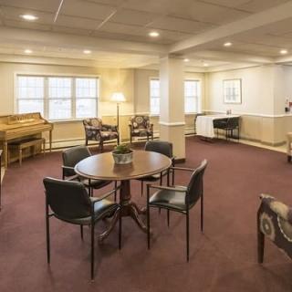 Spacious lounge area with tables, chairs, and a piano.