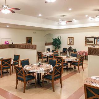 An elegant dining area with neatly arranged tables and chairs, featuring warm lighting and tasteful decor.