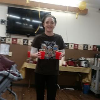 A person holding two red cups, standing in a decorated indoor space.
