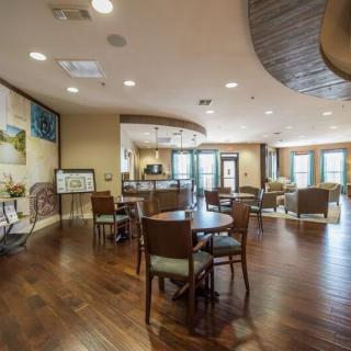 A spacious and well-lit interior room with wooden floors, furnished with tables and chairs.
