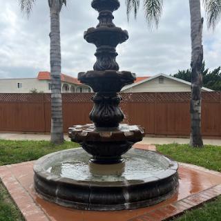 A beautifully designed fountain surrounded by palm trees, adding a serene touch to the outdoor landscape.
