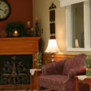 A cozy living room with an armchair next to a fireplace and a lamp.