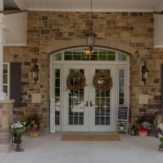 A charming entrance with decorative wreaths and potted plants accenting a brick facade.