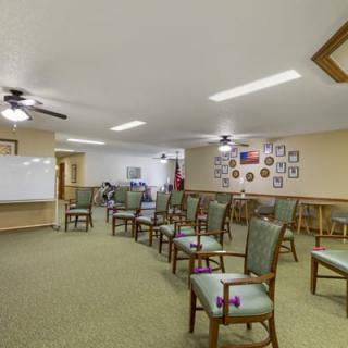 A classroom or meeting room setup with chairs arranged in rows, a whiteboard on the wall, and decorative elements.