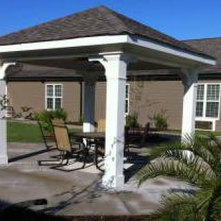 A backyard gazebo with seating under a clear blue sky.