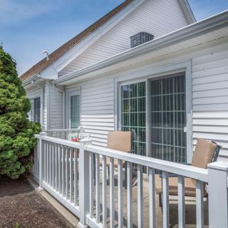 A cozy patio with chairs and a white railing outside a house.
