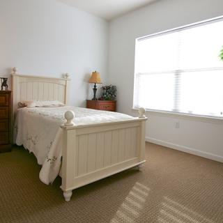 A cozy bedroom with a single white bed and ample natural light from a large window.