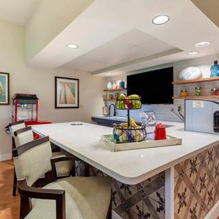 A modern kitchen interior with a bar counter and seating, featuring stylish decor and lighting.