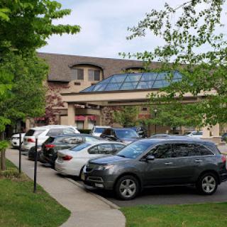 A view of a parking lot in front of a building with glass architecture.
