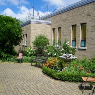 A serene courtyard with lush greenery and blooming flowers surrounding a building on a sunny day.