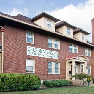 A historic brick building with a sign celebrating a century of service.