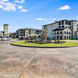 A modern residential complex featuring a roundabout with a fountain under a clear blue sky.