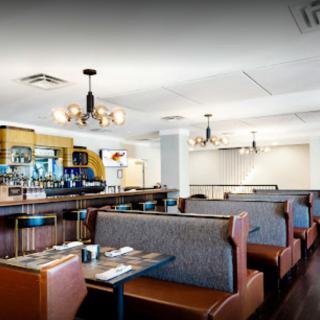 Cozy restaurant interior with comfortable booths and a sleek bar area.