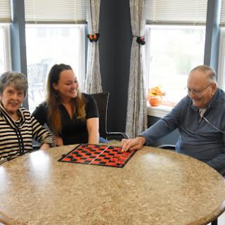 A joyful gathering of three individuals enjoying a game together at a cozy indoor setting.