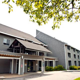 A contemporary multi-story residential building surrounded by greenery.