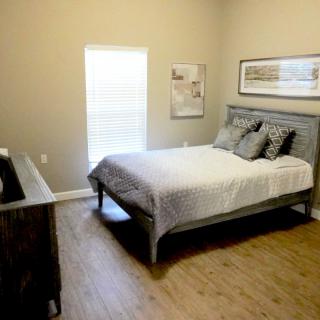 A cozy bedroom with a neatly made bed, wooden floors, and simple decor.