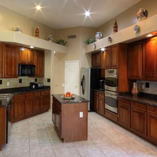 A modern kitchen featuring wooden cabinets, a central island, and stainless steel appliances.