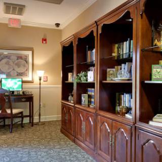 A cozy reading room with wooden bookshelves and a computer workstation.