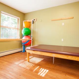 A bright and inviting therapy room equipped with exercise balls and a treatment table.
