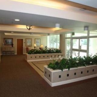 A spacious lobby area with plants, seating, and large windows.