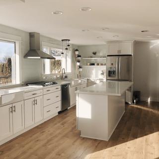 A modern kitchen with white cabinets, a large island, and stainless steel appliances bathed in natural light.