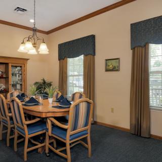 A well-appointed dining room with an elegant table setting and wooden chairs, featuring tasteful lighting and window dressings.