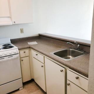 A compact kitchen with a stove, sink, and cabinets.