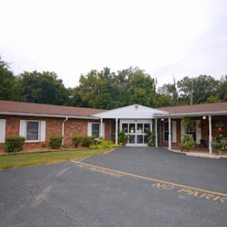 A view of a modest brick motel with a welcoming entrance and landscaped surroundings.