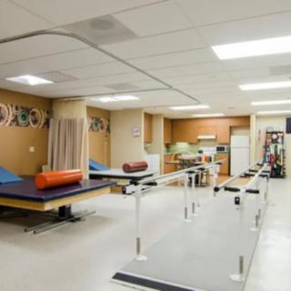 A rehabilitation therapy room equipped with parallel bars and treatment tables.