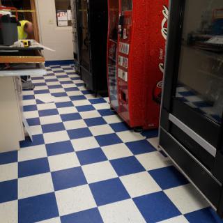 A checkered blue and white floor in a kitchen area with vending machines.