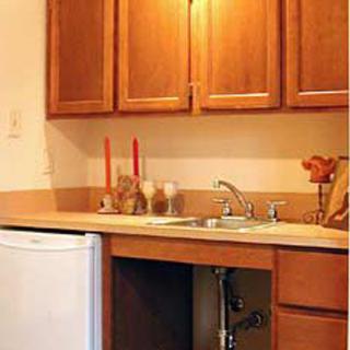 A cozy kitchen area featuring wooden cabinets, a sink, and a small refrigerator.