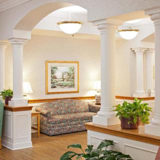 A cozy lobby area featuring a patterned sofa, decorative columns, plants, and soft lighting.