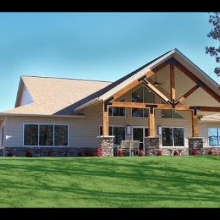 A modern house with a spacious design, characterized by wood accents and a lush green lawn.