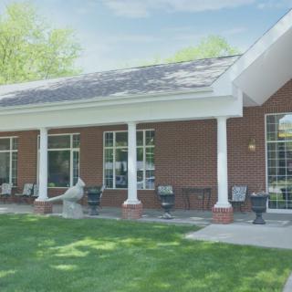 A brick building with white columns and a green lawn under a clear sky.