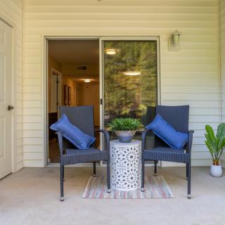 Cozy patio setup with chairs and a small table adorned with a potted plant.