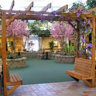 A beautifully decorated indoor garden with a wooden pergola and swings, surrounded by vibrant flowers.