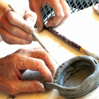 Hands crafting a clay pottery piece.