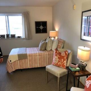 A cozy bedroom with a neatly made bed, two lamps, and decorative pillows.