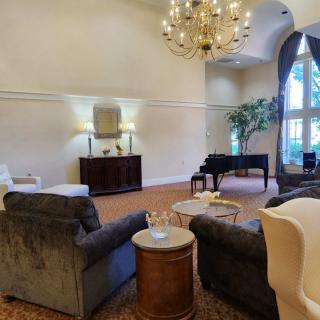 An elegant living room featuring a chandelier, plush seating, and large windows.