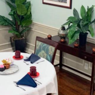 A elegantly decorated dining room with a round table set for two and lush indoor plants.