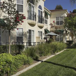 A sunny view of a residential apartment complex with well-maintained gardens and balconies.