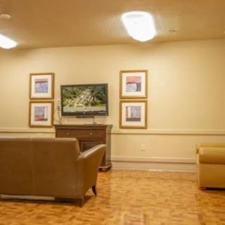 A cozy living room with a television and framed artwork on the wall, featuring comfortable sofas and a wooden floor.