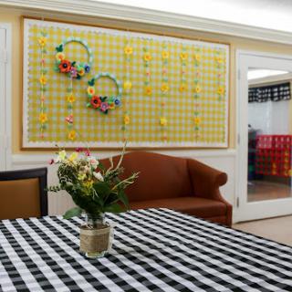 A cozy living room featuring a checkered tablecloth, a brown sofa, and decorative wall art.